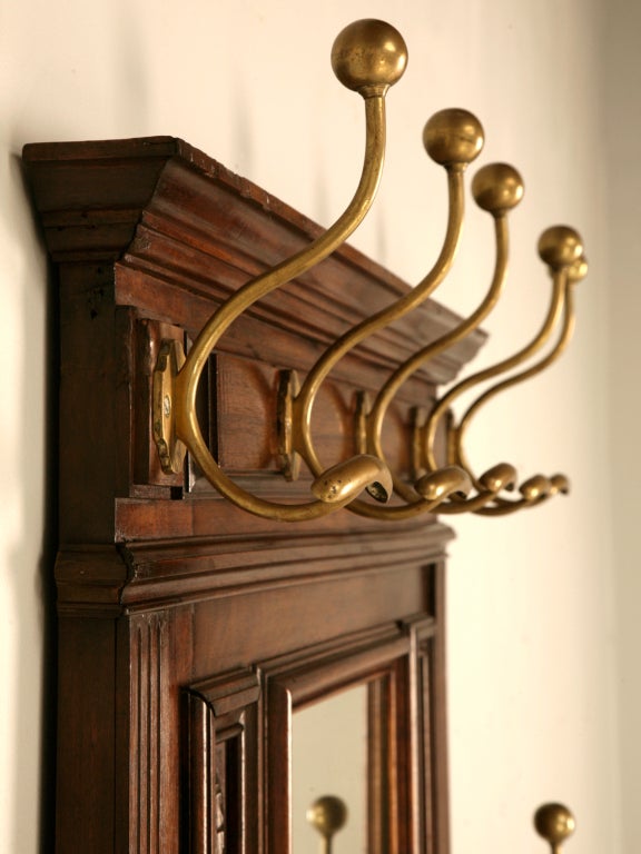 Breathtaking original carved antique French figured walnut hall tree or stand. This impressive hall stand showcases exotic solid figured walnut with intricately detailed carvings as well as its original brass hooks, keeper and pan. Although this