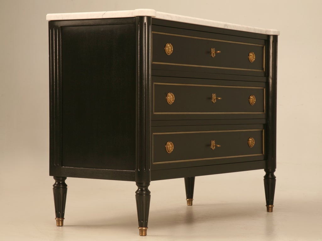 With its satiny smooth black finish contrasting ever so well with its original white with gray veined marble top, its polished brasses give this commode all the attitude it needs and then some. Whether you use it as a glamorous nightstand in the