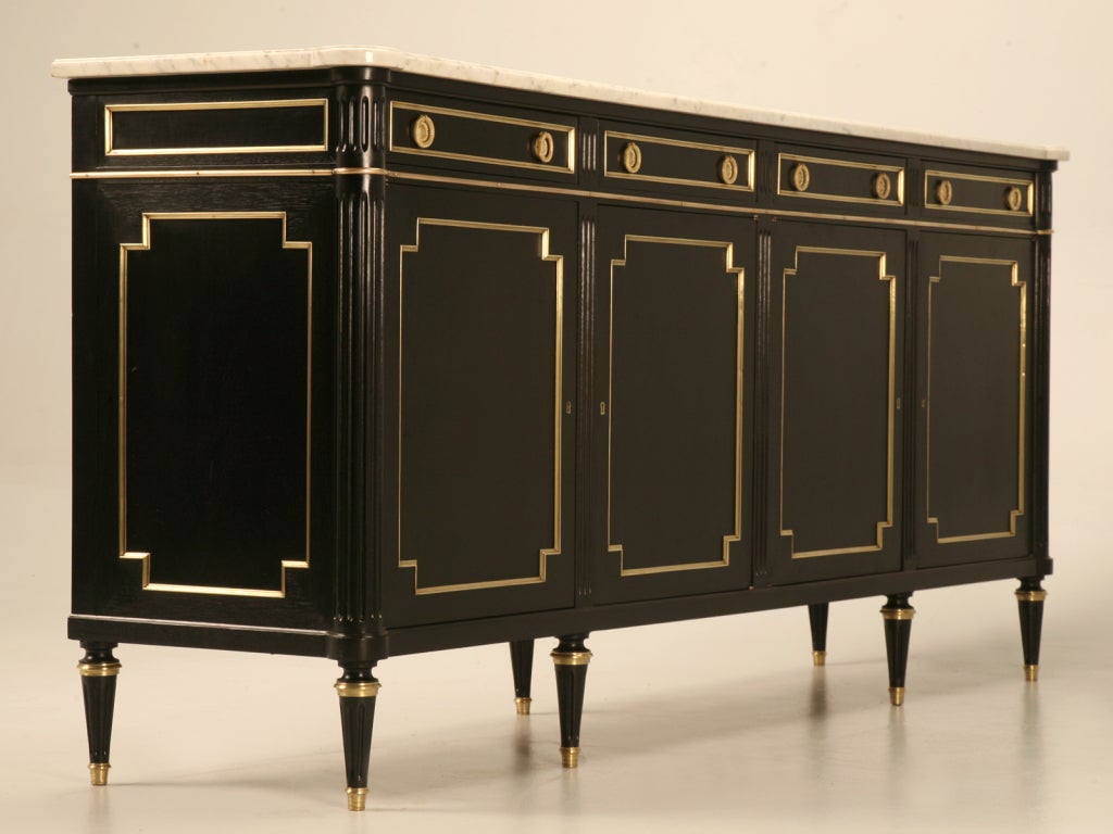 Impressive and extraordinary vintage French ebonized mahogany Louis XVI buffet with dramatic contrasting polished brasses, and original shaped marble top, too. Expertly constructed this ever so popular 4 drawer over 4 door configured buffet is an