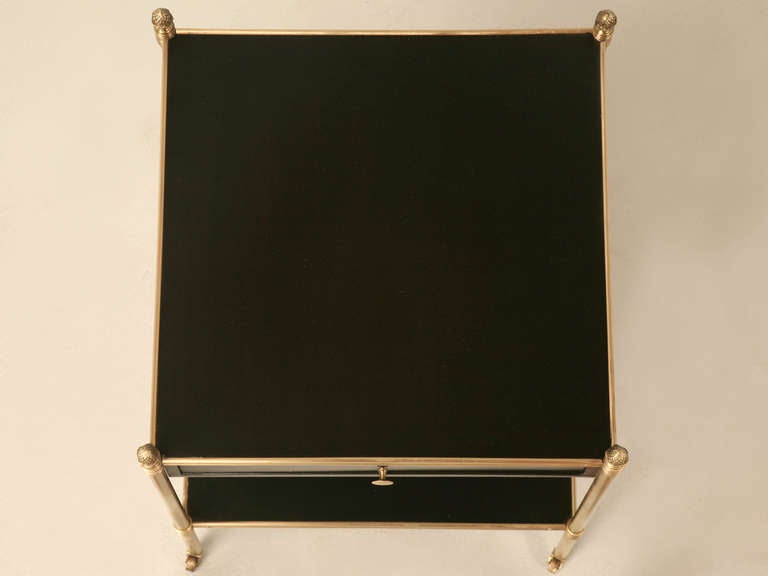 Stellar vintage French neoclassical side table in the style of Maison Jansen. This outstanding table screams of quality and timeless design. The rich black ebonized mahogany finish contrasts perfectly against the solid polished brass legs capped on