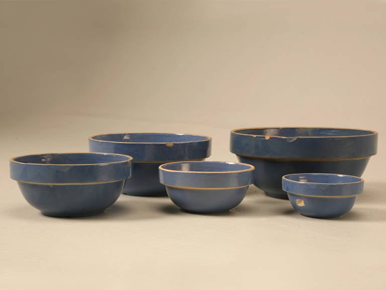 Unusual set of five matched handmade vintage American pottery mixing bowls. There are minor chips from years of use, but they are glazed in the most beautiful shade of blue and would make a great accessory for any kitchen requiring a little dab of