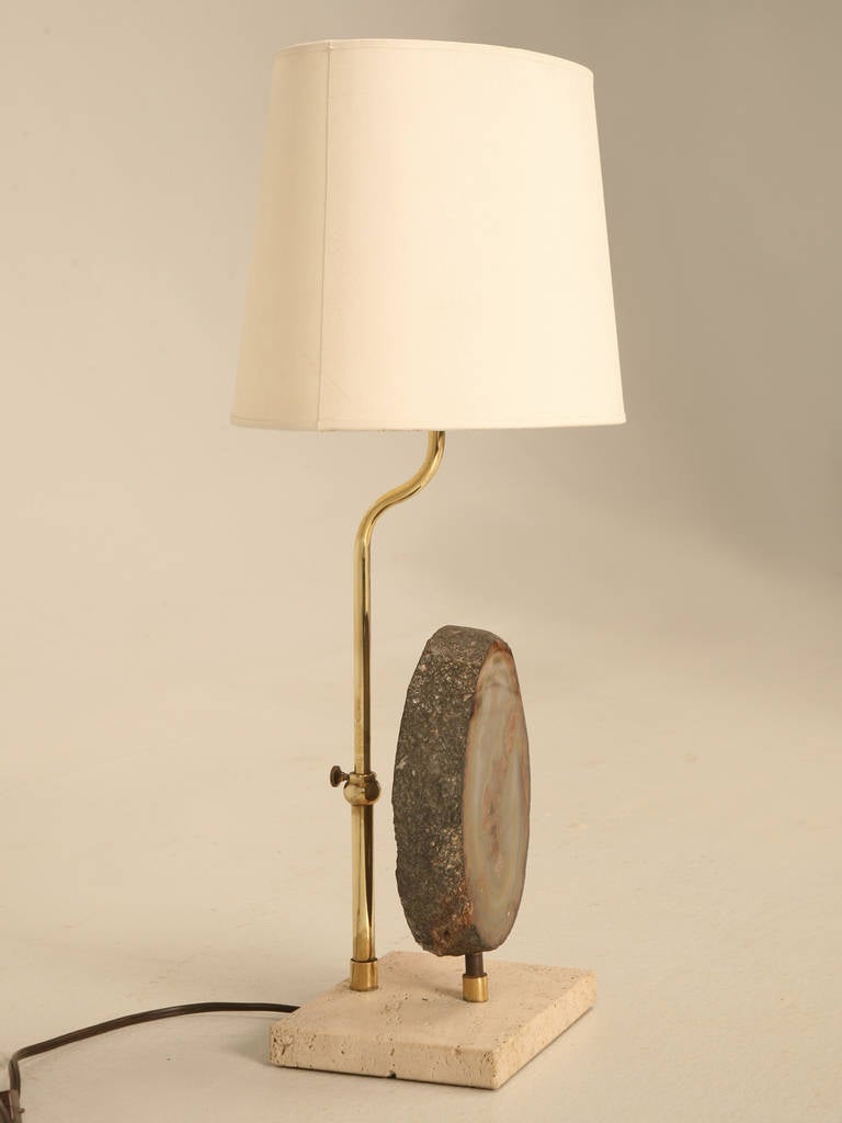 Circa 1970s French specimen lamp, created from a polished agate with a limestone mounting base. Brass rod will adjust the height of the shade. Wired to accept a full size bulb of 75 watts. 
The shade is 7.75