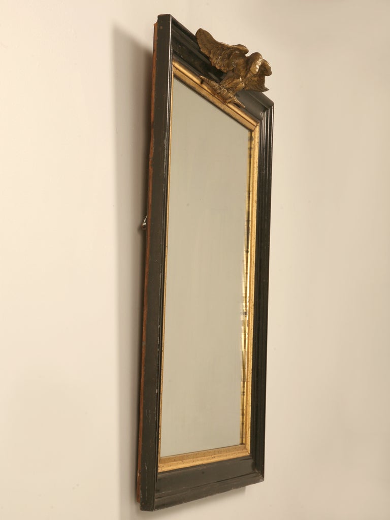 Original antique French Napoleon III mirror with a majestic eagle up top overseeing it all, contrasting ever so well with the simple elegance of the black and gilt frame.

French Imperial Eagle refers to the figure of an eagle on a staff carried
