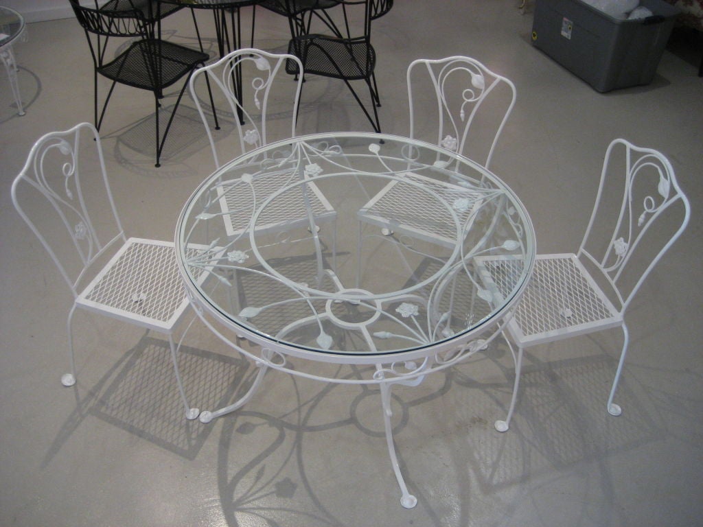 Vintage Salterini iron dining set with four chairs and circular table with glass top.
