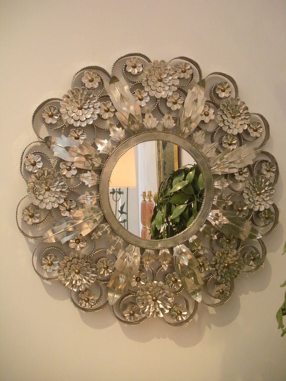 Circular Mexican tin mirror encrusted with flowers and leaves.