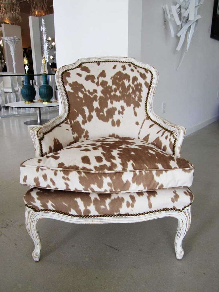Pair of 1940's bergeres in faux cowhide fabric studded with brass upholstery tacks.