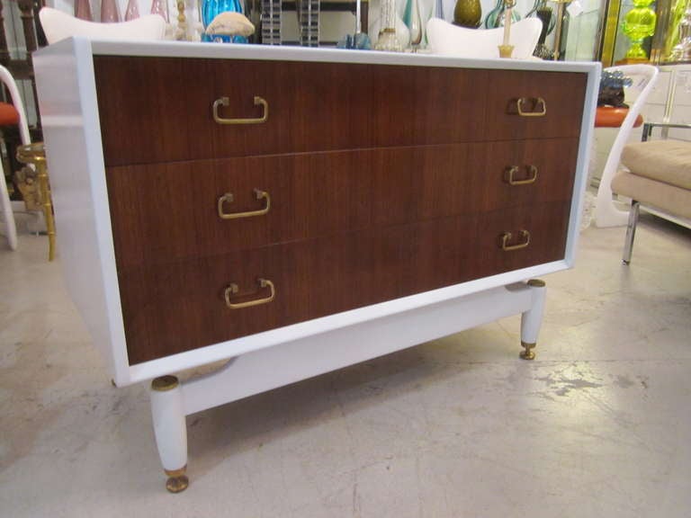 Pair of two- tone Mid Century Modern bedside chests with brass hardware. The chests have white bodies with wood fronts and simple brass hardware.