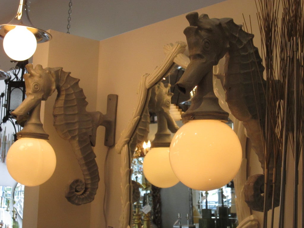 Pair of vintage seahorse carriage lamps with big glass globe. The lamps mount to the wall and are in working order.