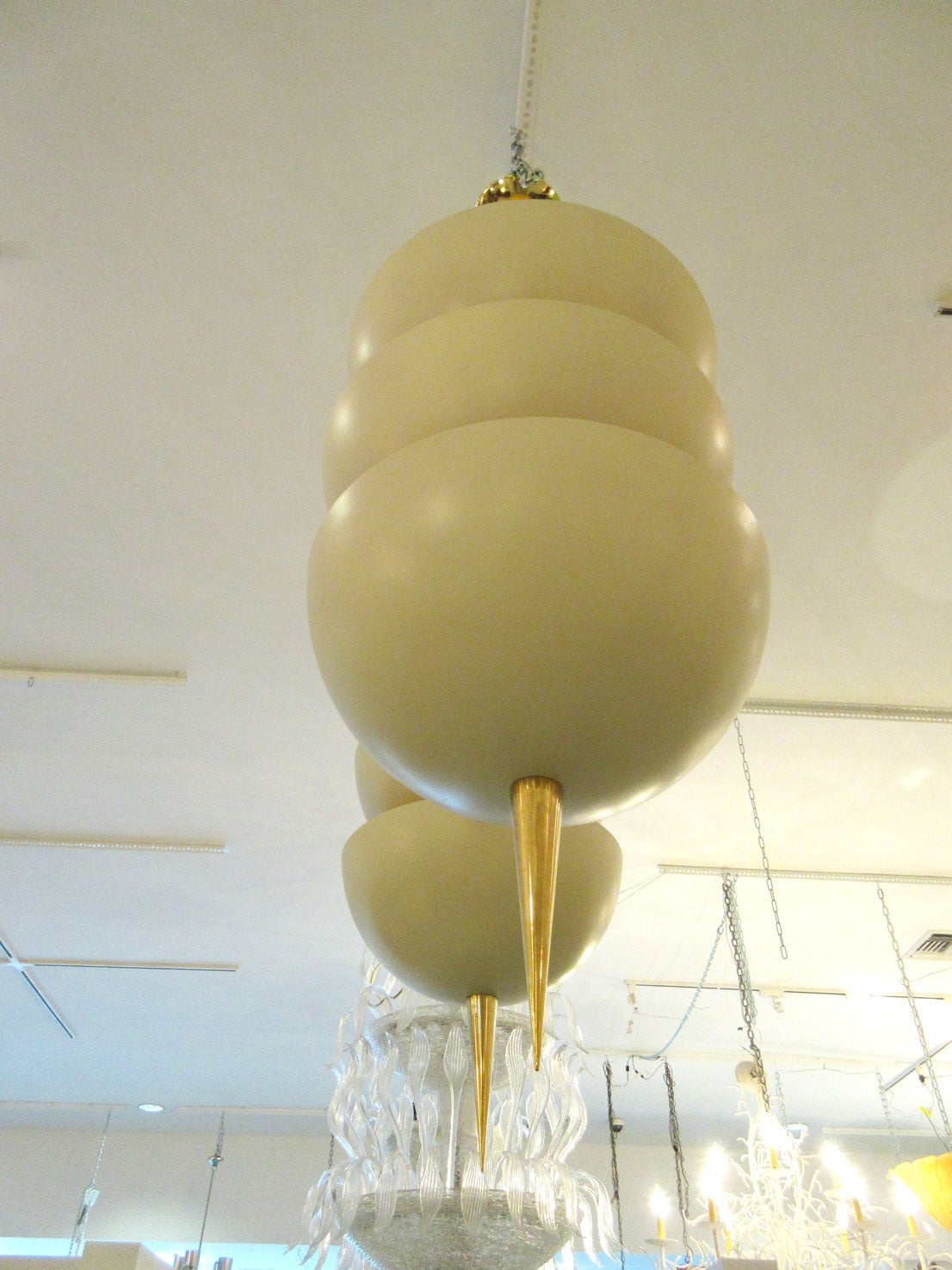Two large-scale modernist pendant light fixtures made of enameled eggshell colored shades and brass hardware.