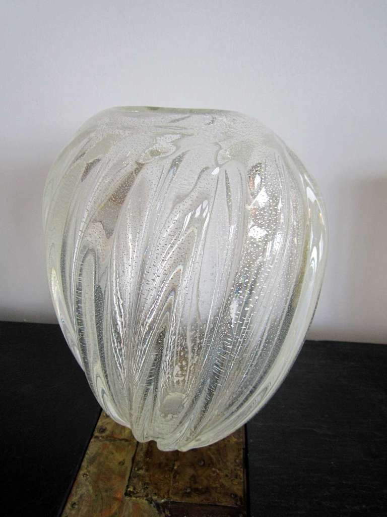 Large tapered vase of clear Murano glass with silver fleck inclusions by Seguso.  Smooth glass has raised gentle diagonal ridges on the outside and silver aventurine throughout.
Two available