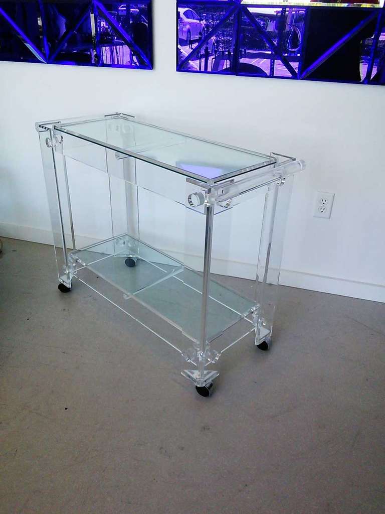 Vintage thick lucite bar cart with chrome wheel covers.