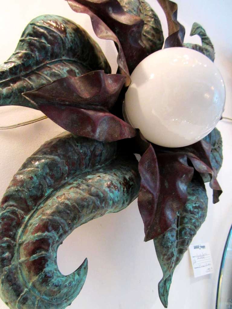 Pair of stylized patinated flower sconces with scrolling leaves. The fixtures may be used as ceiling mount or used as sconces. The outline resembles a starfish.