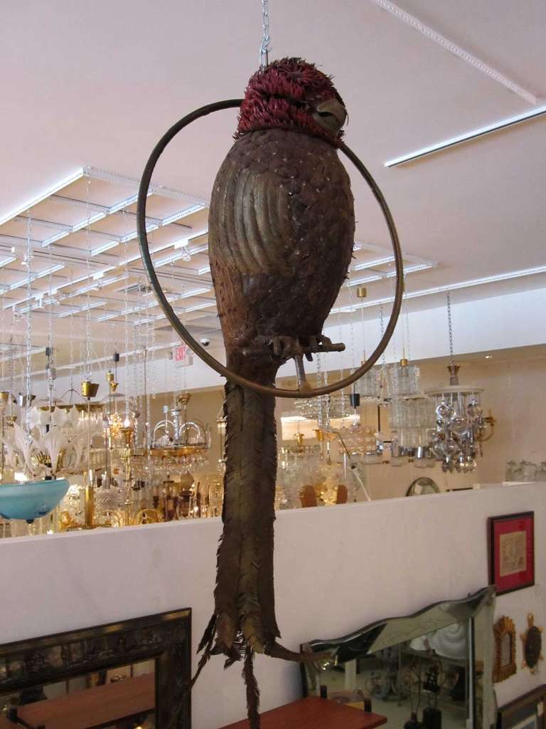 Monumental mixed metal Hawk Owl by Mexican artist, Sergio Bustamante, that sits on a circular metal perch. The metal feathers are highly detailed and the head of the owl is a scarlet red, with upward curling pieces of metal.