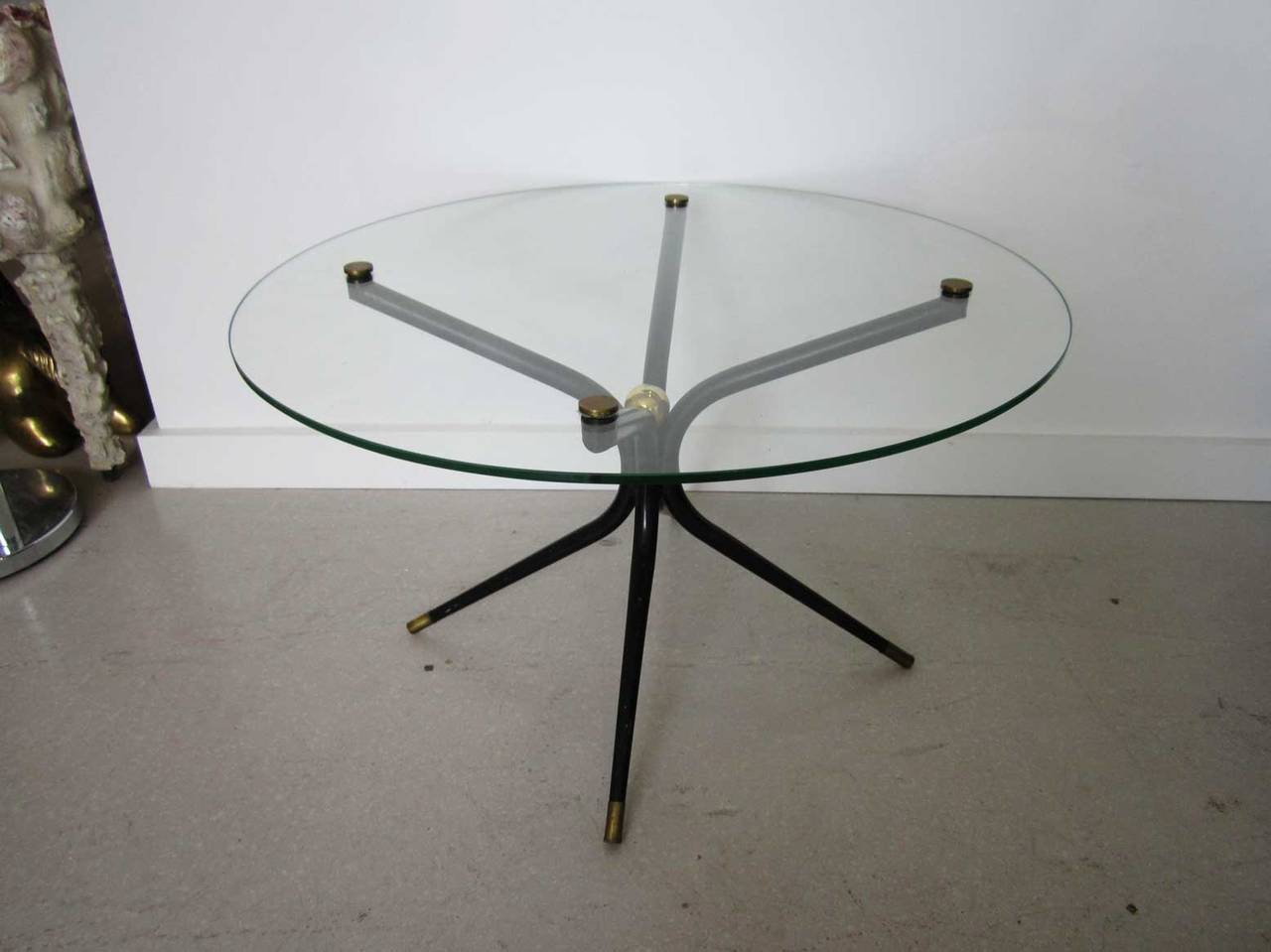 Circular  table with a black sprawling spider like base and brass accents.