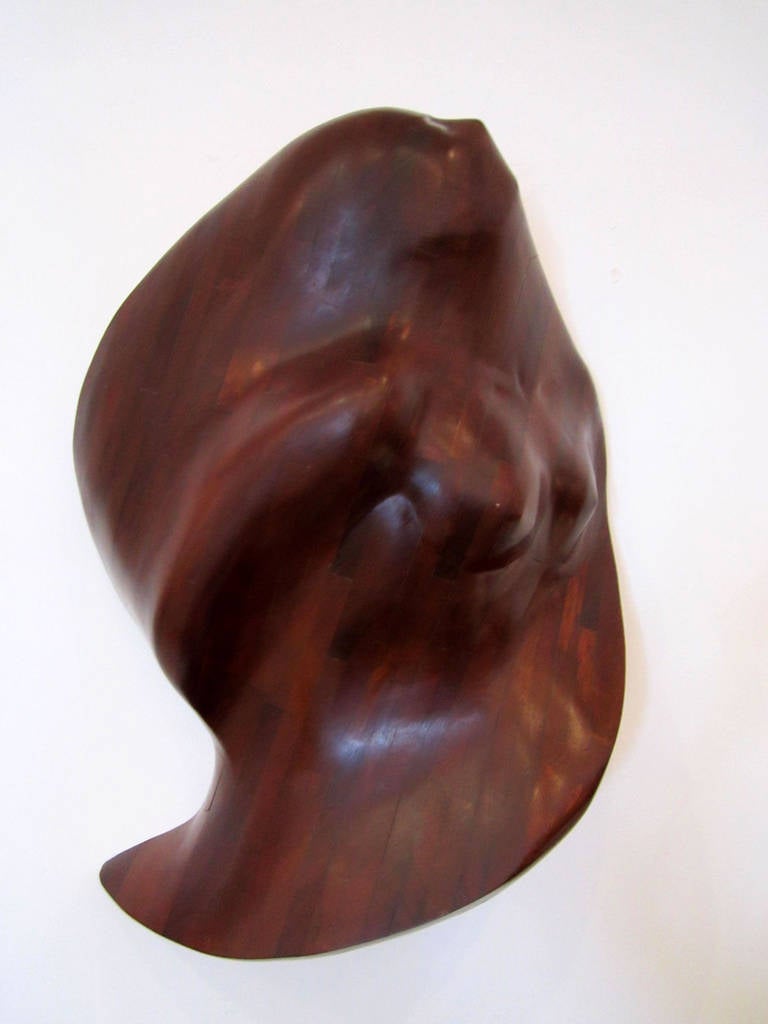 Carved biomorphic wall sculpture of a female emerging from wood. The wood is 