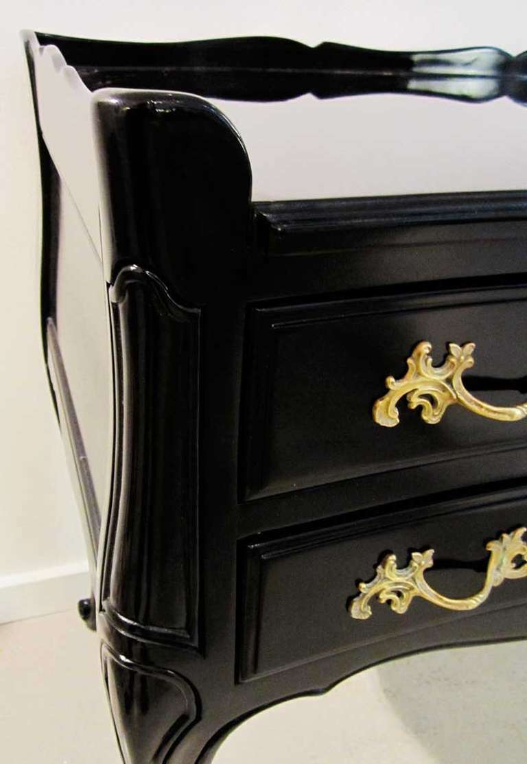 Elegant black lacquered Widdicomb desk with stylized scalloped apron and ornate brass hardware on six pull out drawers for storage.