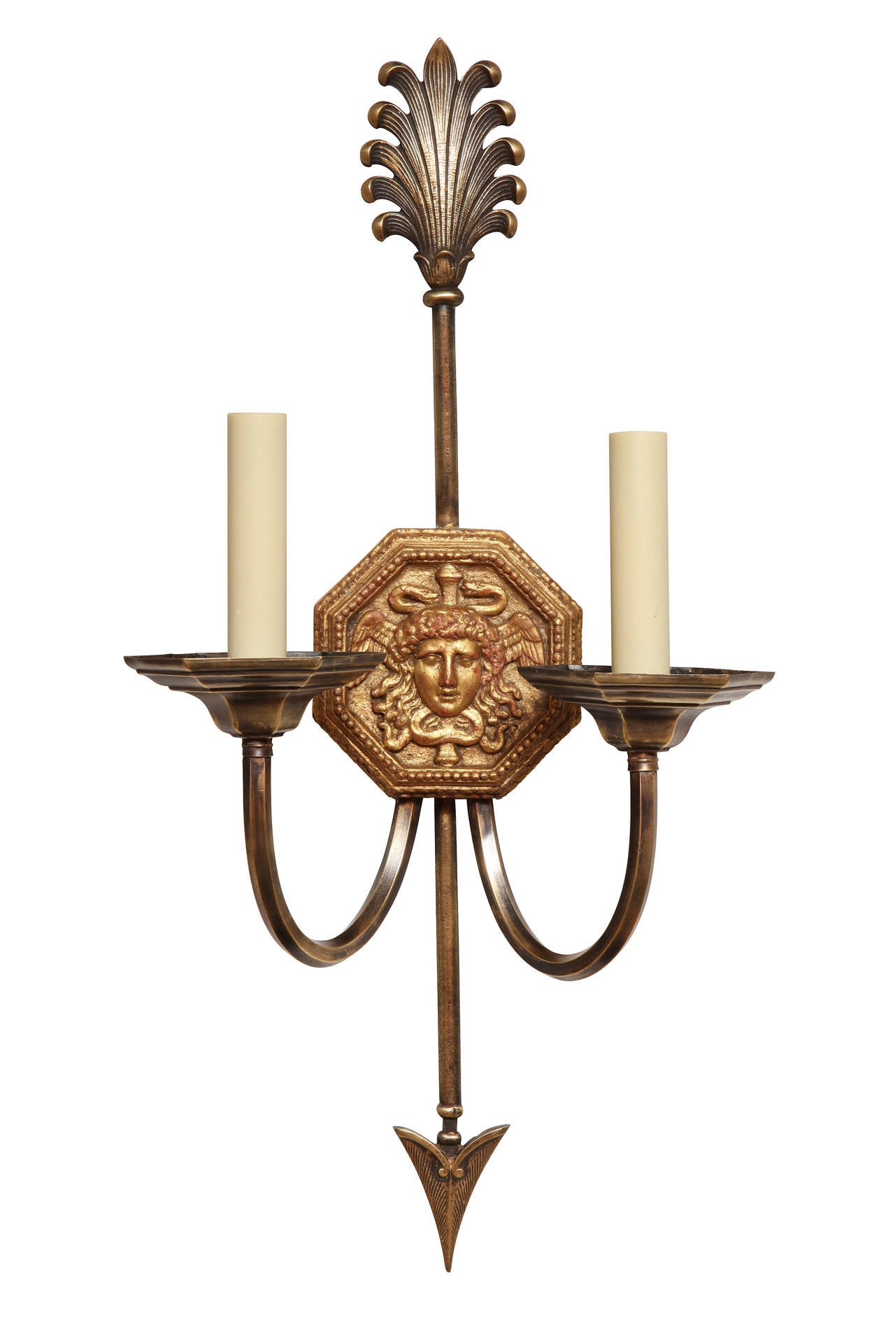 A pair of Caldwell two light Empire style sconces with octagonal carved and gilt backplates having classical portrait medallion with beadwork frame. The vertical back in the form of an arrow. Each upswept arm with an octagonal bobeche.