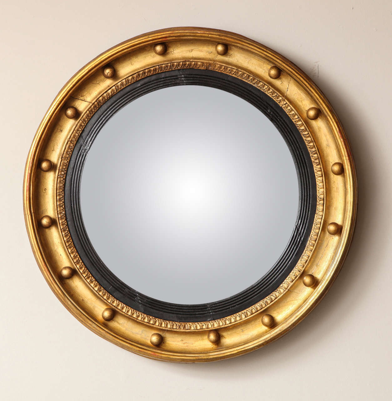 An English Regency bulls eye mirror having shaped ogee molded edge with ball finials.