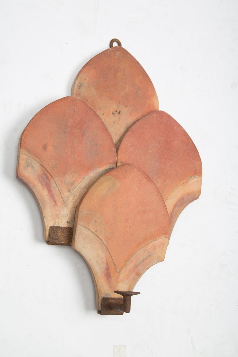 A pair of single light American Art Deco wall sconces, the leaf shaped glazed terra cotta elements forming a back plate with iron frame and bobeche. 
