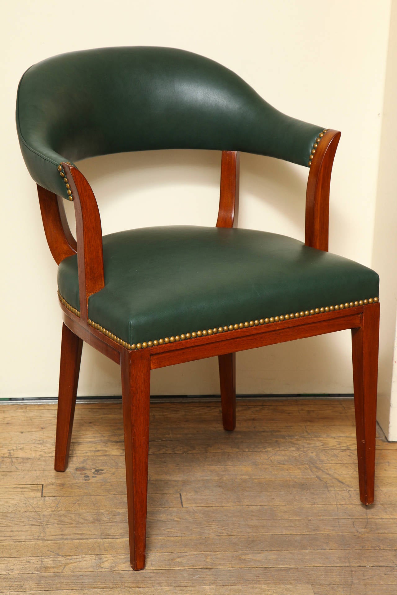 A Dunbar desk chair, the arched upholstered back supported by tapered vertical elements and square and taper legs above upholstered seat. Now covered in leather with nailhead trim.