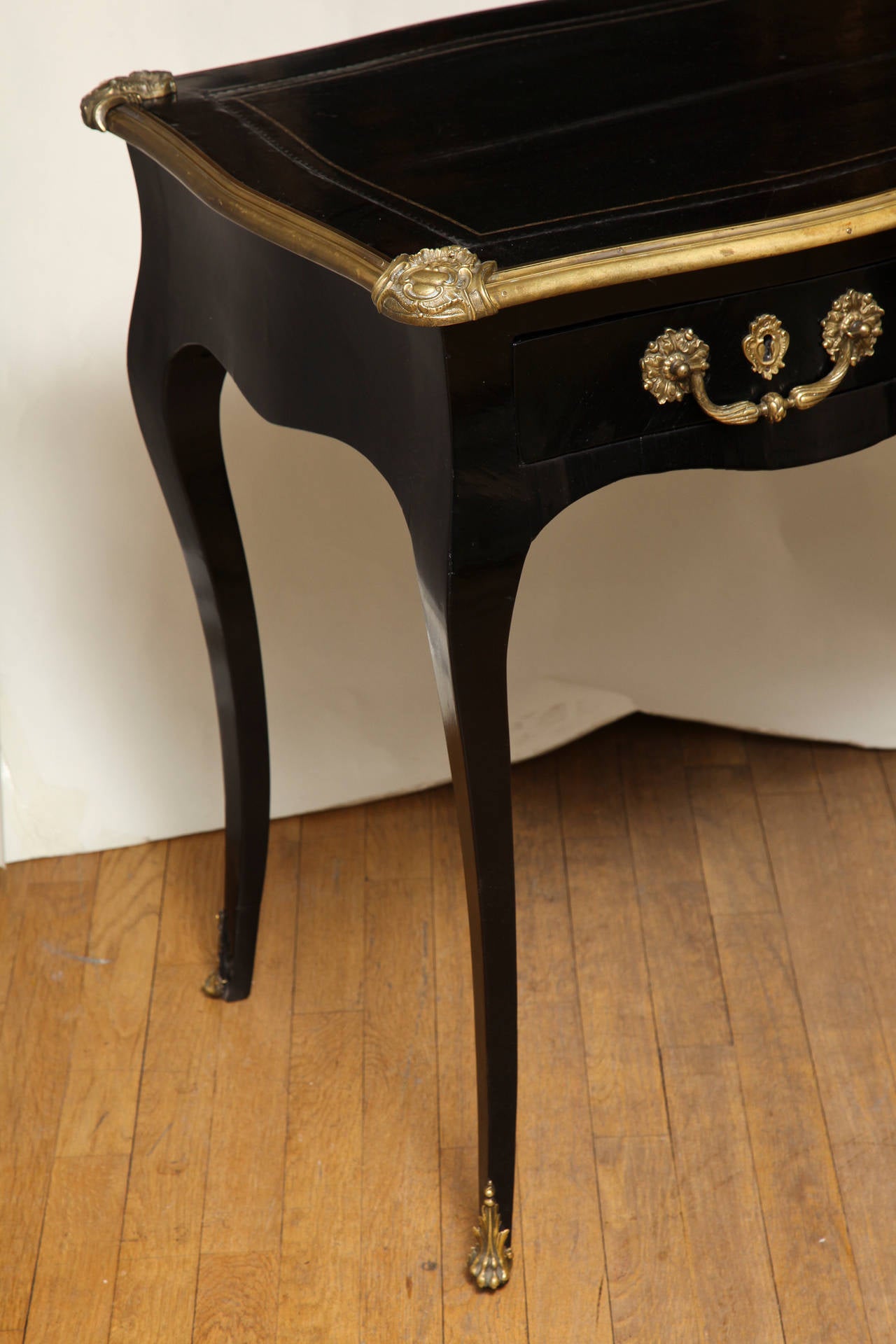 A French Louis XV style side table with serpentine shaped top, having bronze molded edge and corner mounts. The serpentine front sides and back with scalloped edge and two drawers in the apron of one side, supported by tapering cabriole legs with