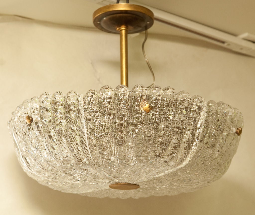 A Swedish Orrefors ceiling light with textured glass in 6 sections having scalloped edge, each section secured by rosettes and having round rosette on underside, the frame suspended from brass rod and canopy.

Note: 7.5