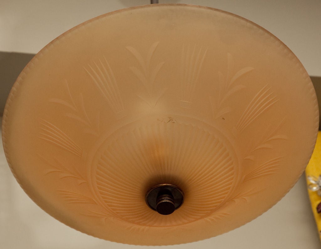 An Orrefors Art Deco ceiling light designed by Edward Hald with palmette and stylized Neo Classical motifs etched in amber colored glass, the dish shaped bowl secured to patinated bronze stem and canopy with Deco finial on underside.