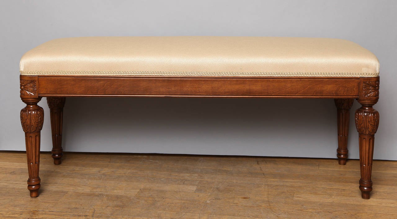 A rectangular bench with upholstered seat. The new upholstery above apron with rounded corners having hand carved corner rosettes above round tapering fluted legs.