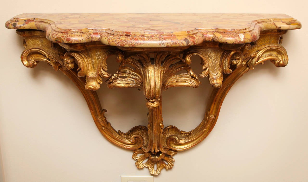 A French Regence style carved and giltwood wall-mounted console with original scalloped and ogee edge Breche marble top.