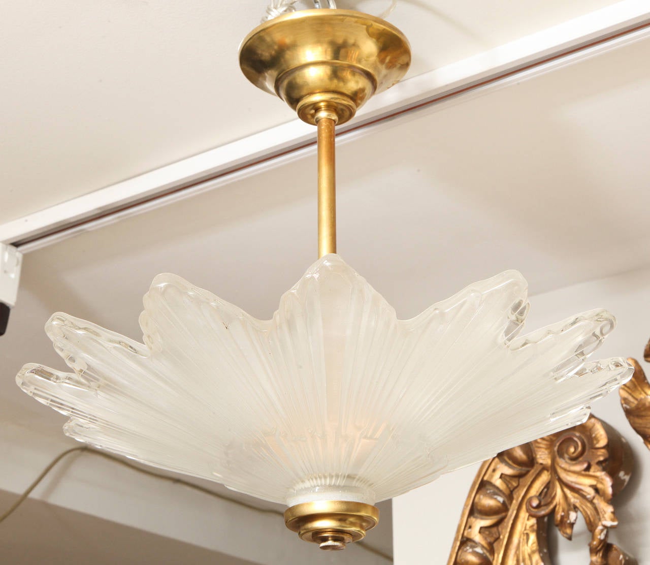 A Caldwell scalloped edged glass sunburst ceiling light with ridged vertical lines suggest sunrays. The glass interior frosted to diffuse three candelabrum sockets.