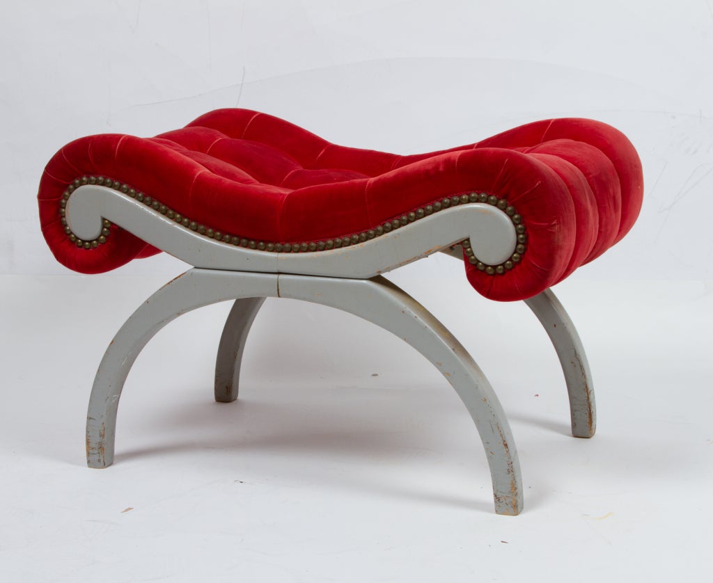 A saber leg bench with grey painted finish and original red cotton velvet button upholstery. Design attributed to Francis Elkins.
