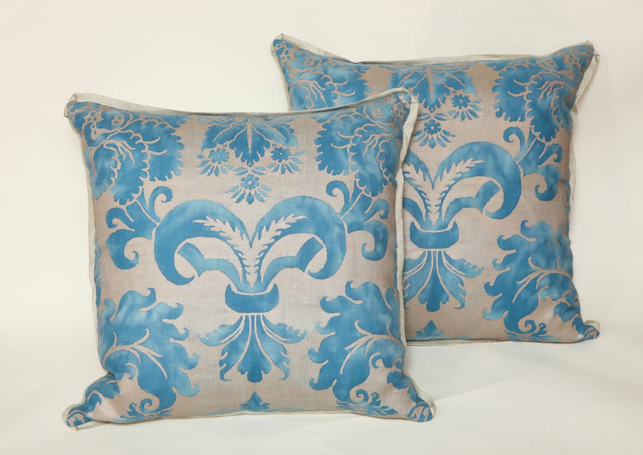 A pair of vintage Fortuny fabric blue and gold Glicine pattern cushions with bias edging and woven metallic backs.