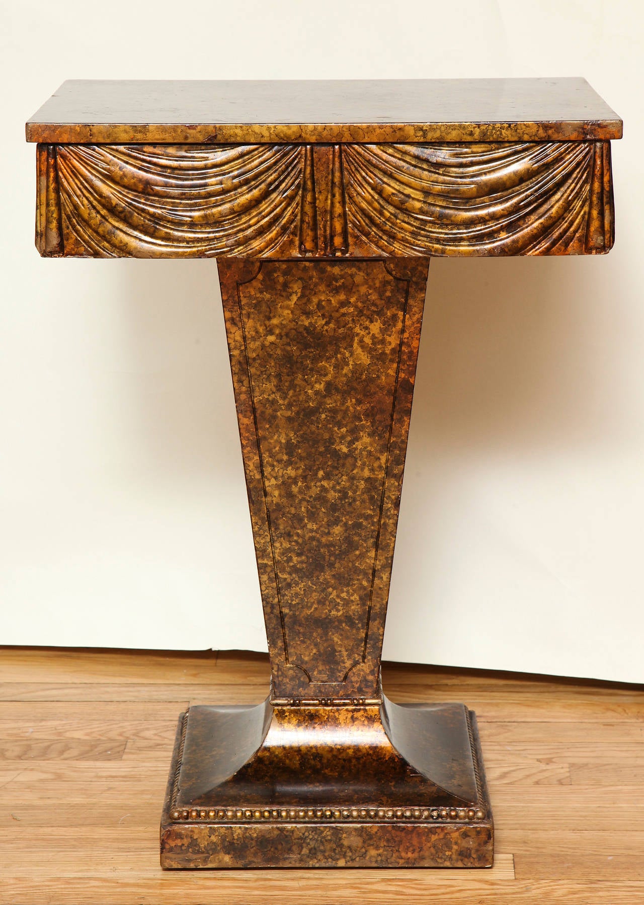 A Grosfeld House side table with metallic faux tortoiseshell finish and carved trompe l'oeil swags.