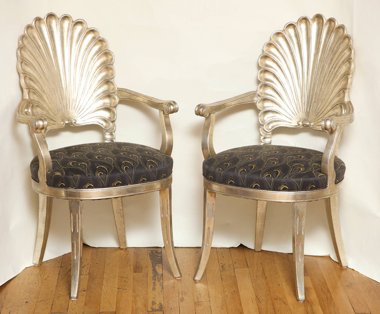 A pair of Italian carved wood shell-back open armchairs, the frame having white gold finish and upholstered seat above square and tapered splayed legs.