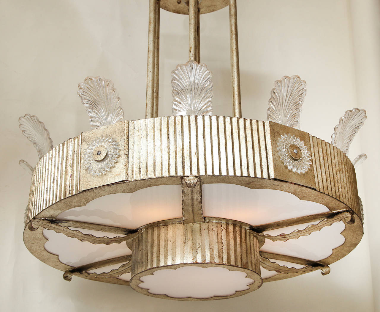 An Art Deco inspired round two-tiered ceiling light, the round metal frames with ridged texture having four square panels decorated with cut glass sunburst ornaments over the 24 karat white gold finished frame, the upper tier and lower tier of