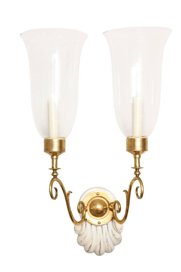 A pair of George II style two-light sconces, with painted wood backplates in the form of shells and handblown glass hurricane shades. 

Measures: Backplates: 6.5