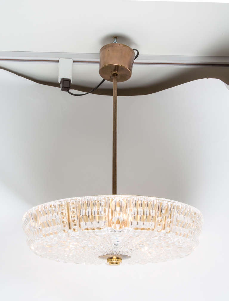 A Swedish Orrefors ceiling fixture with textured molded glass dish having canted sides and round plate concealing 6 candelabrum sockets suspended from brass rod and canopy.