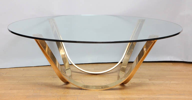 A contemporary design round coffee table, the base in the form of four upswept U-shaped elements supporting a round top.