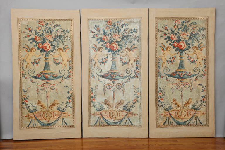 A French Louis XVI style three panel papier peinte screen. Each section with neoclassic design wallpaper featuring a stylized urn issuing floral bouquet with winged putti on a light blue ground.