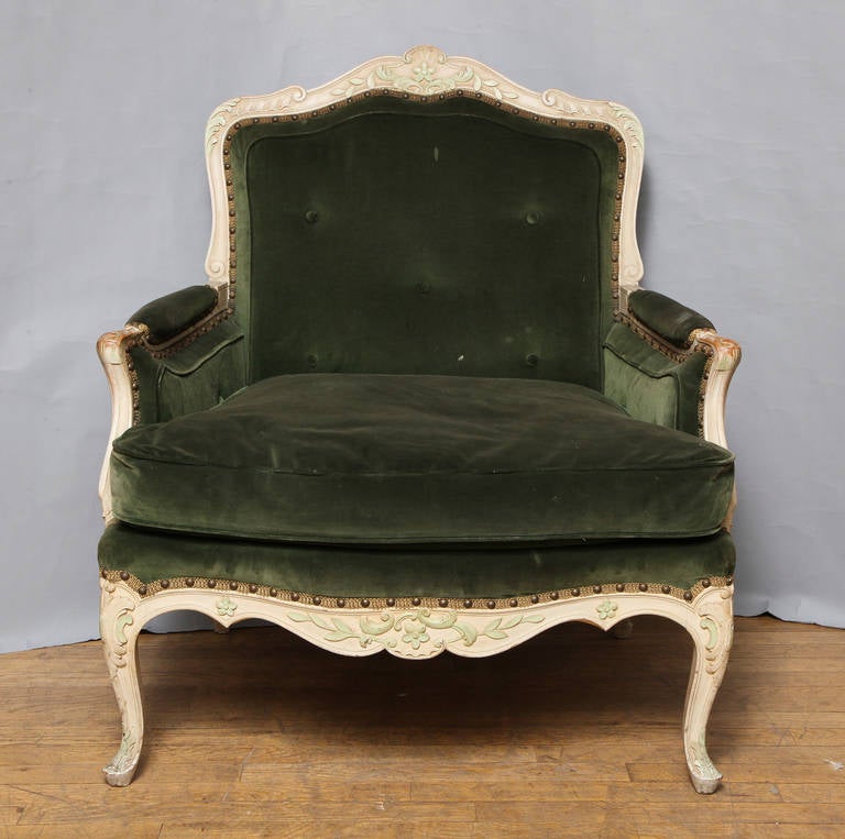 A pair of French Louis XV style bergeres. The hand carved frame with ivory painted finish having celadon green details highlighting the shell and rocaille motif carvings. In the manner of Jansen. Two pairs available. Upholstery as is. (2nd pair