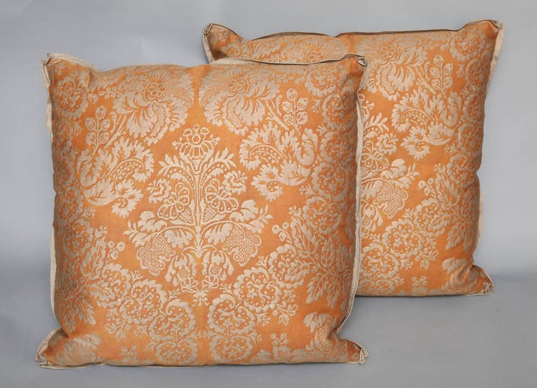 A pair of vintage Fortuny fabric burnt orange Solimena pattern cushions with Thai silk backs and matching silk bias edging.
