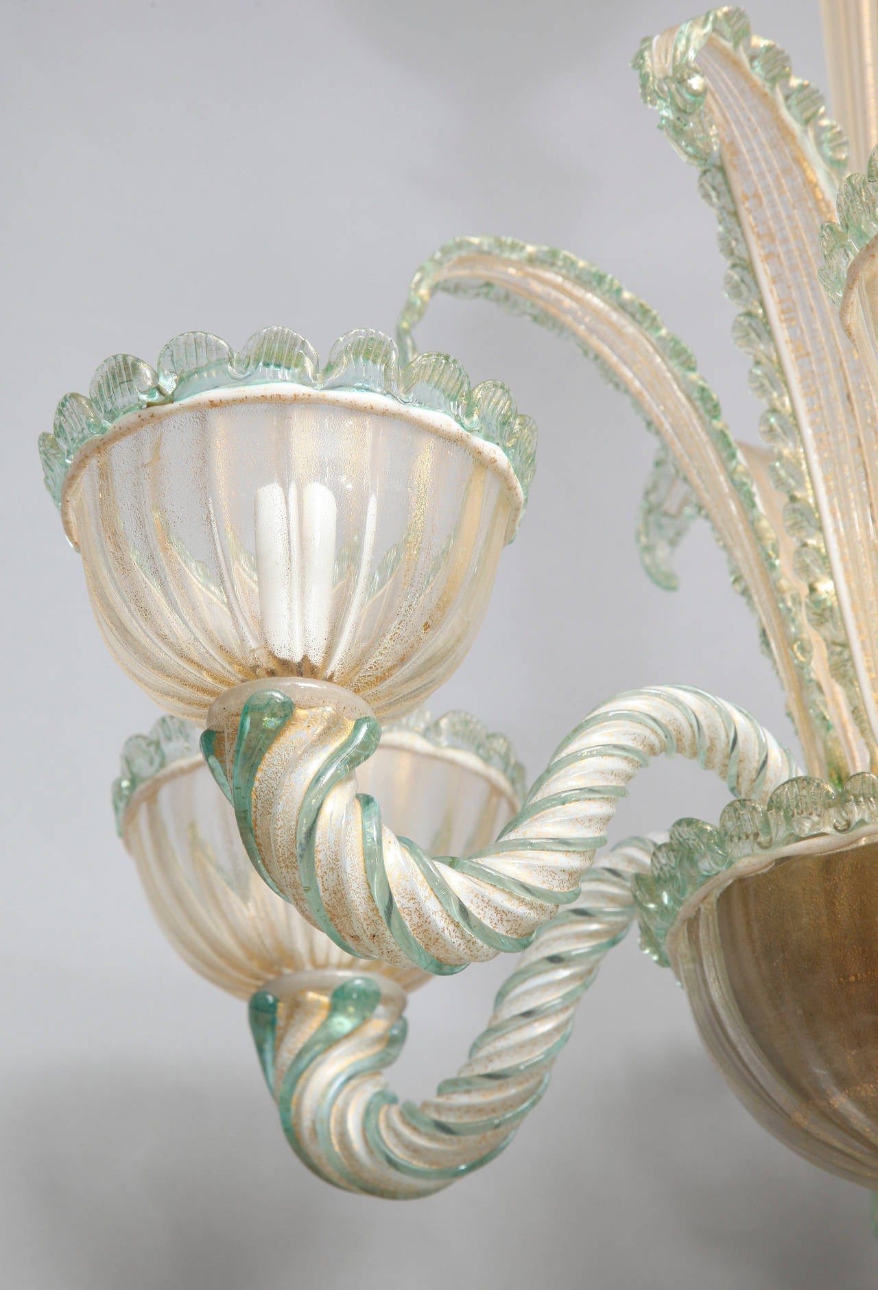 A six light Venetian Murano glass chandelier. The hand blown gold flecked glass with swirling green striped arms and rope detailed edges. The round tapering center stem attached to body issuing sprays of glass leaves.