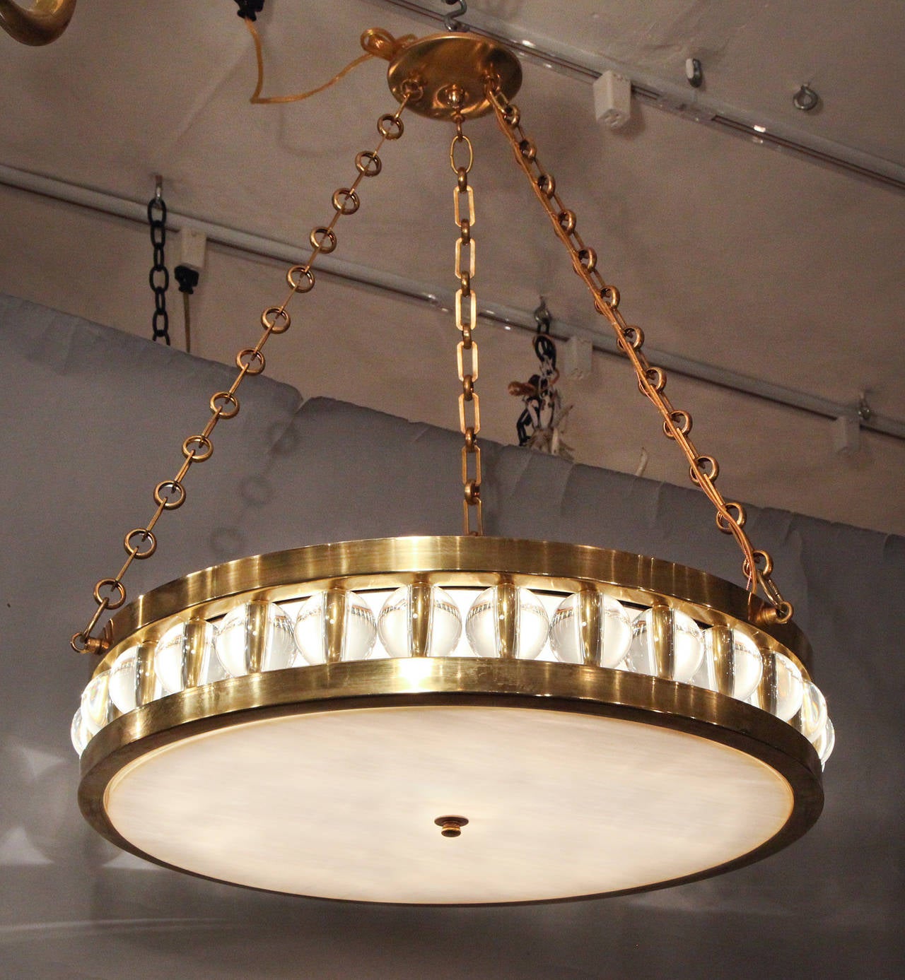 A large round pendant ceiling fixture suspended from chain and canopy, the metal frame securing a flat piece of white swirl glass with finial in center on underside, the sides with overscaled Murano glass beads. 

Drop is adjustable and available