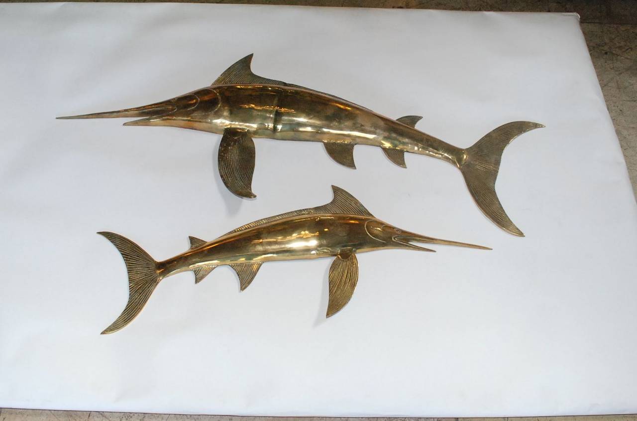 Two vintage Hollywood Regency brass swordfish wall sculptures. Larger fish measures 47