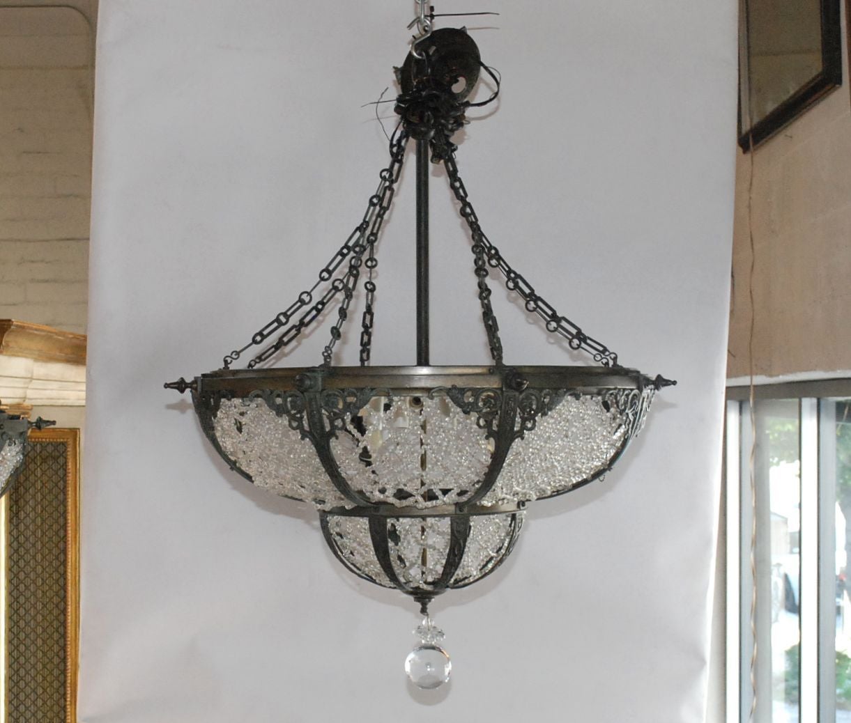 A pair of bronze and beaded glass chandeliers in the Russian style. Each chandelier has 12 bulb sockets. Bronze is decorated with raised foliate design. Glass beads are arranged in a diagonal crisscross pattern.