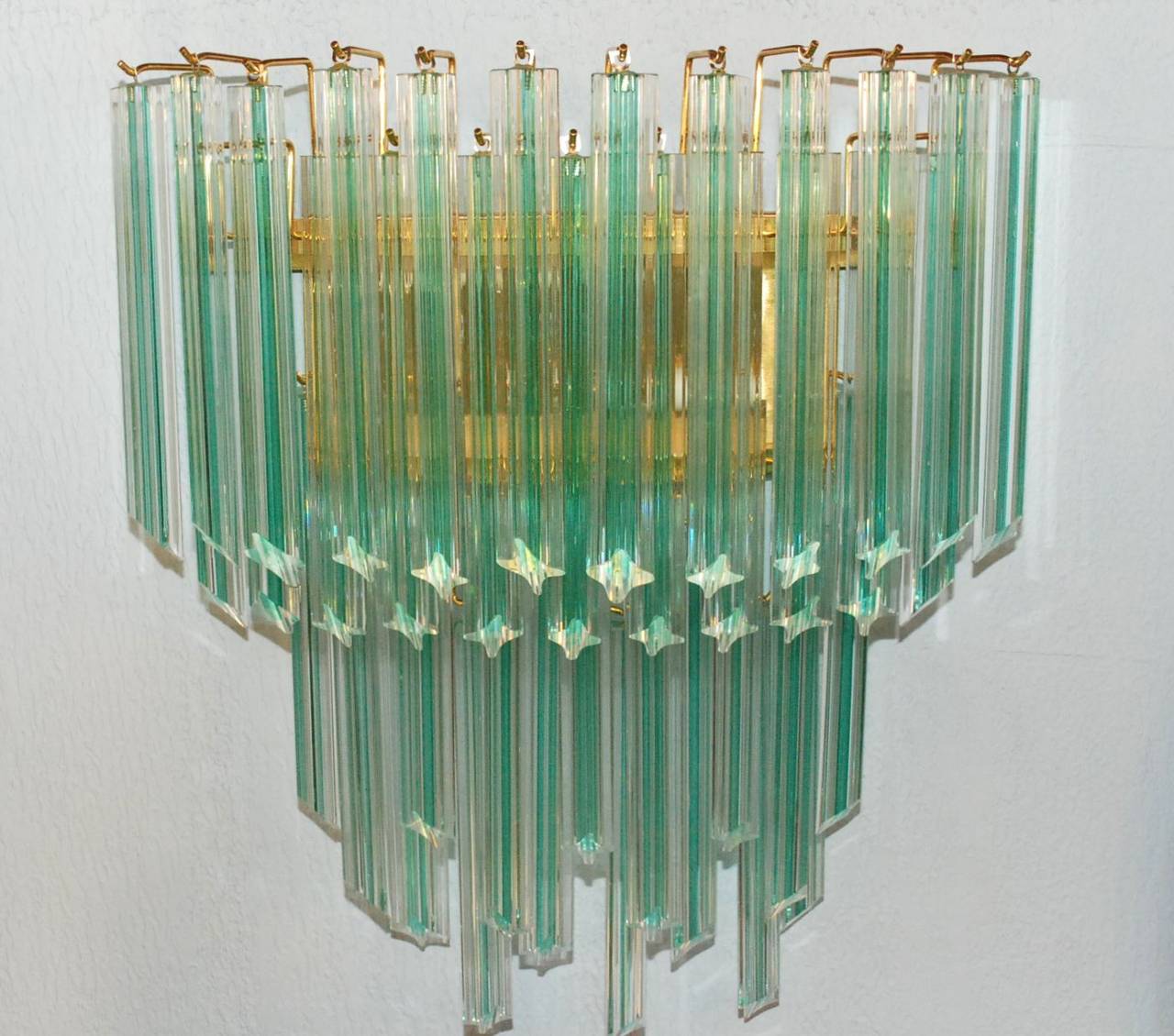 A pair of Venini aqua stripe (clear and aqua) sconces. Each sconce has two lights with brass frame and decorated with solid quadriedri (four-sided) hanging Murano glass tubes.