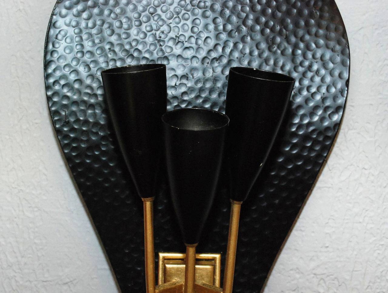 A pair of  black hammered metal and brass sconces in the style of Stilnovo. Each sconce has three lights.
Three pairs are available.