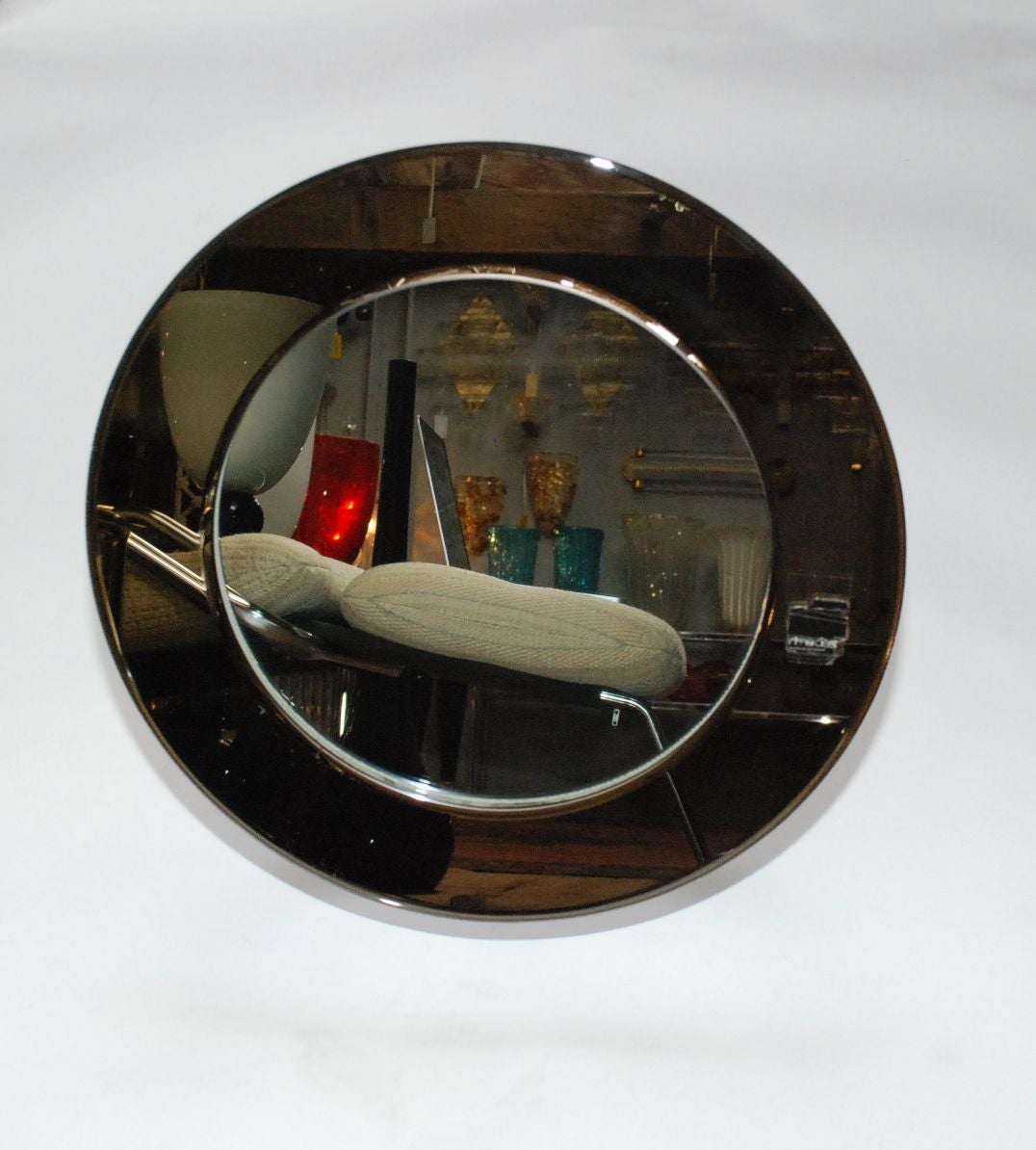 A smoky glass vanity mirror. Glass edge is smoked mirror with the center section clear mirror. Base is aluminum. There is a tiny edge chip being disclosed for accuracy only. Has an old paper Rimadesio label.

The diameter of the mirror is 17.5