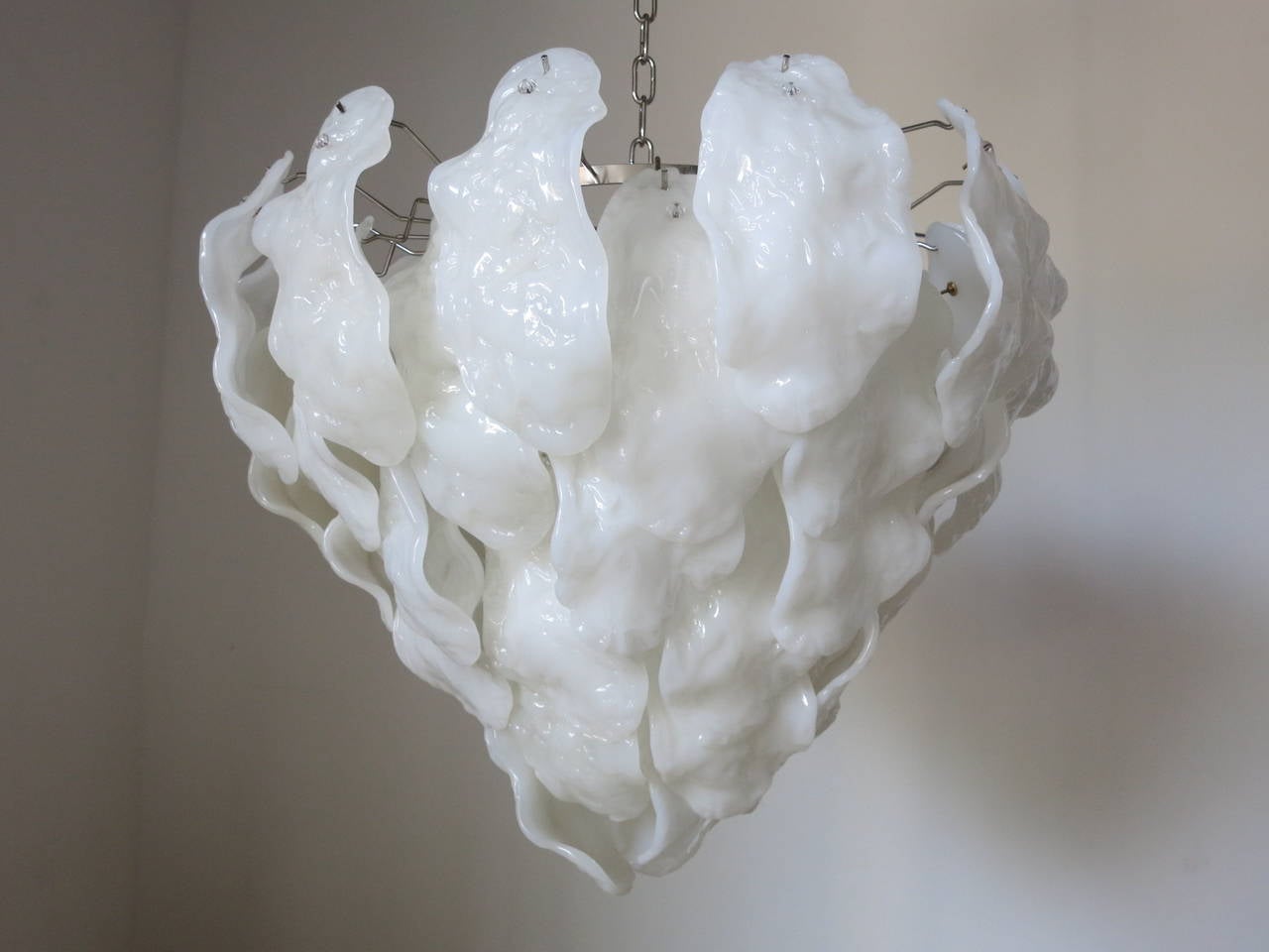 A Mazzega milky white bent leaves chandelier. There are 49 pieces of glass and it has seven lights with a nickel frame.