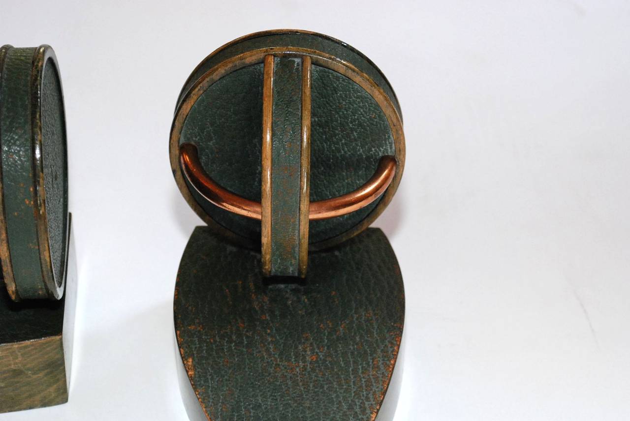 A pair of geometric green leather and copper bookends in the style of Jacques Adnet. There is age wear to the green leather especially around the edges. Please see photos.